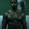 Muscular figure standing before a green screen backdrop