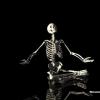 Skeleton meditating in a spotlight, oddly zen